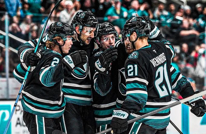 San Jose Sharks players (Will Smith,  Vincent Desharnais, Collin Graf, Mario Ferraro, and Alexander Wennberg) celebrating together after a goal in the cali fin jersey 
