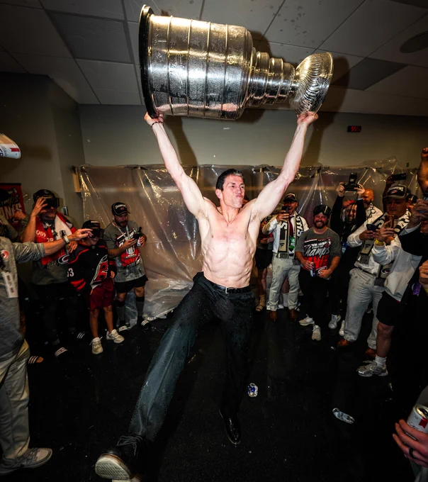 Photo of Rod Brind'Amour shirtless in the locker room hoisting the Cup