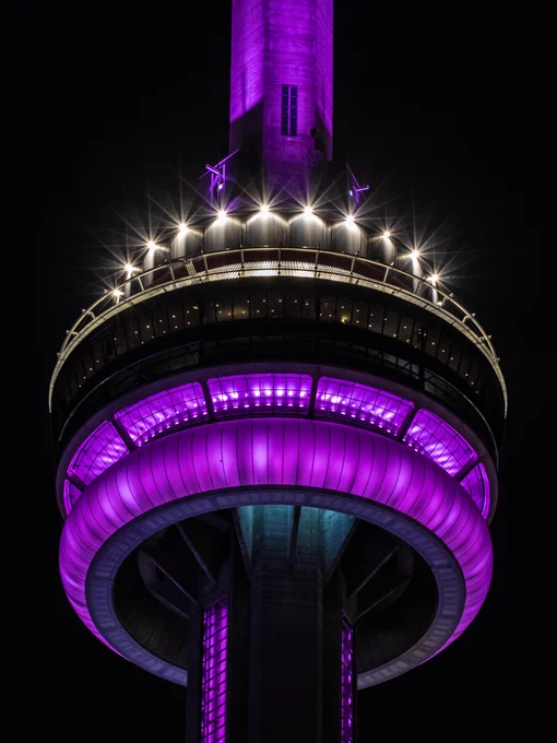 Closeup of the CN Tower at night lit purple/ Gros plan de la Tour CN illuminée en violet la nuit 