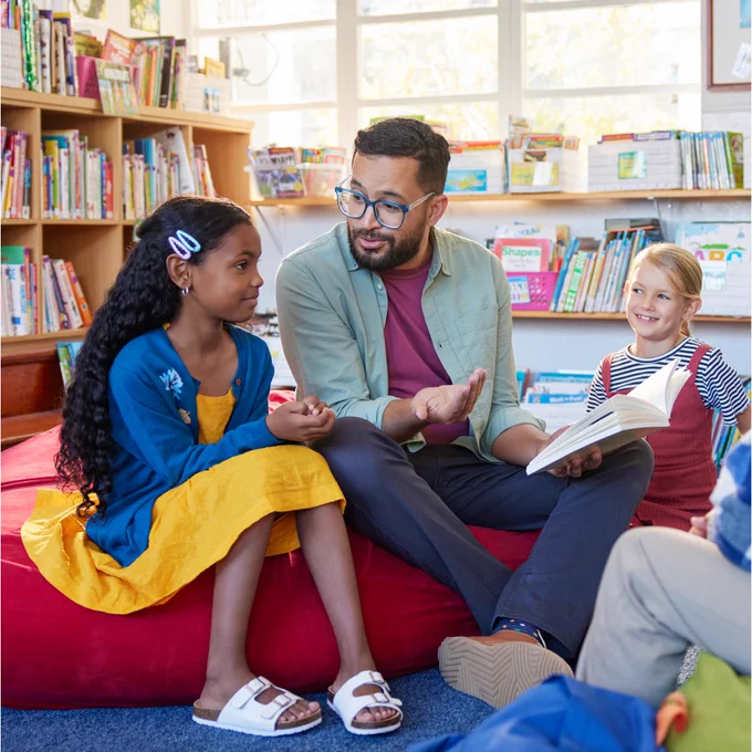 A teacher reads to pupils in a library. 
