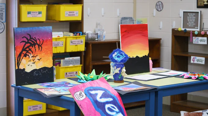 An artwork display during the CREATE program showcase including painted pictures of the sunset