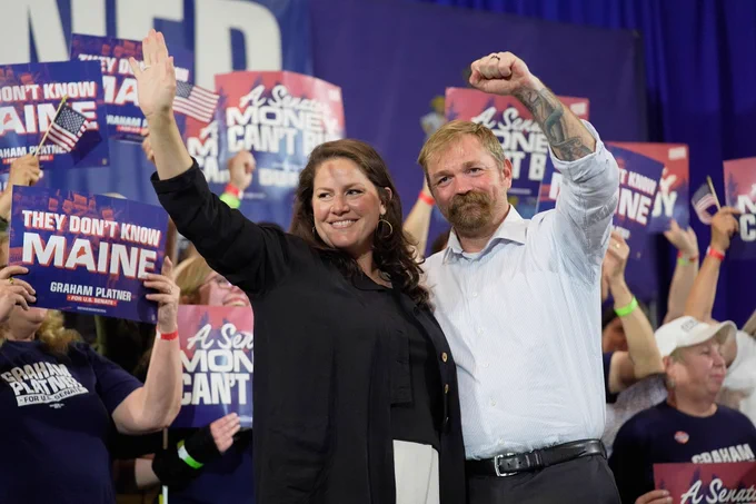 Graham Platner and his wife Amy Gertner gesture to supporters during a election night watch party
