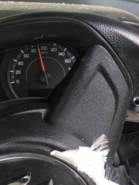 कार के डैशबोर्ड का क्लोज़-अप। स्पीडोमीटर की सुई 90 km/h पर फ्रीज होकर अटकी हुई है। एयरबैग डिप्लॉय होने के बाद स्टीयरिंग व्हील पर फटा हुआ सफेद एयरबैग फैब्रिक दिख रहा है।