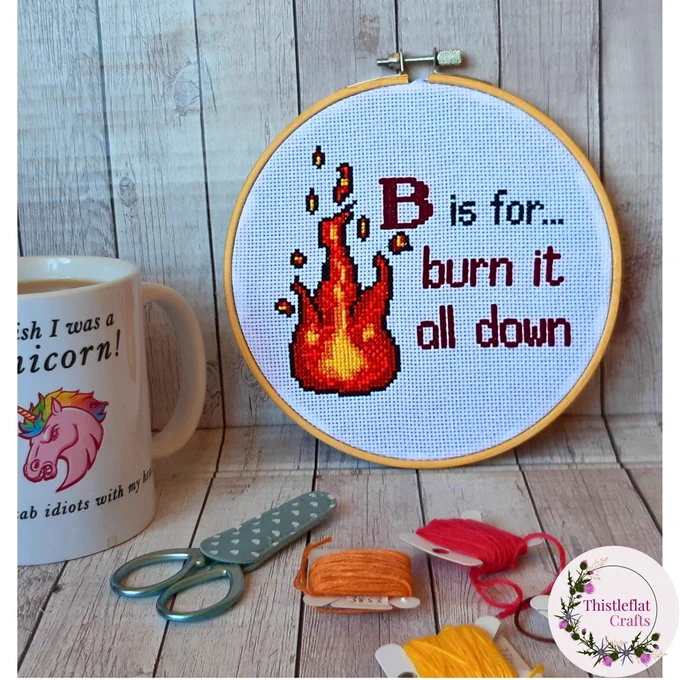 Completed cross stitch saying 'B is for...burn it all down' decorated with flames