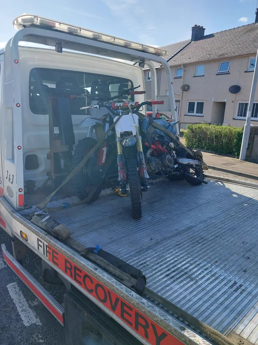 Two dirt bikes being transported on a white recovery truck with 'FIFE RECOVERY' branding.