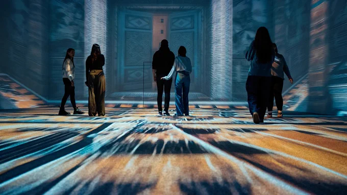 People exploring a room with colourful, immersive floor projections at Treasures of Tutankhamun: The Experience
