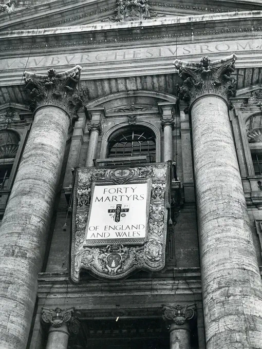 Black and white photo of the front of St Peters, Rome with a large banner reading 'Forty Martyrs of England and Wales'