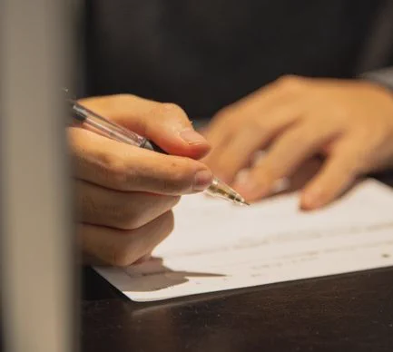 Crop anonymous male with pen in hand and paper on table filling in document