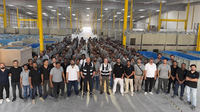 A large group of workers posing inside a spacious industrial warehouse at MAT Filtration Technologies' new UAE facility.