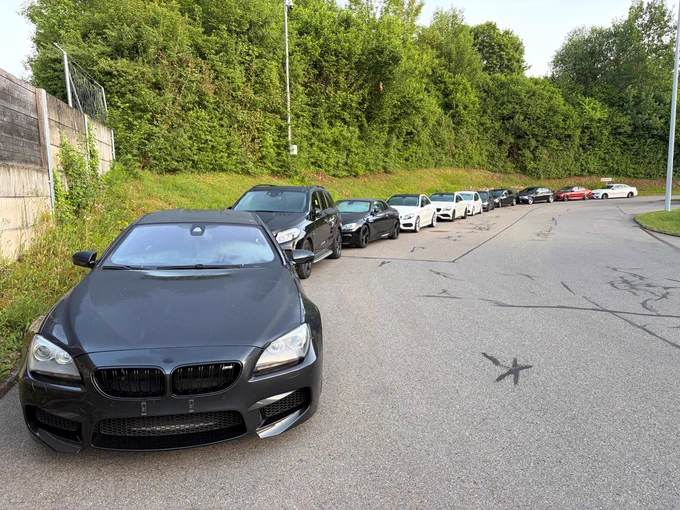 Ein Parkplatz mit mehreren Autos, darunter ein schwarzer BMW.