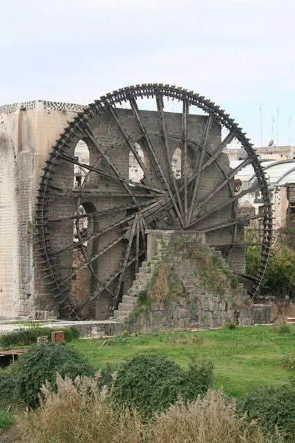 🌀 The Giant Wooden Wheel That Has Never Stopped Turning

Beside the calm, flowing waters of the Orontes River, in the ancient city of Hama, stands a breathtaking machine from another age — the legendary Hama Norias. Made entirely of wood and stone, this massive water wheel has been turning for centuries, lifting river water high into the air without engines, fuel, or electricity. Long before modern technology, people here mastered nature itself. 

As the river flows, the wheel slowly rotates, scooping water and sending it through channels that once fed mosques, gardens, public baths, and entire neighborhoods. Built and perfected between the 12th and 14th centuries, its deep creaking sound still echoes today — a sound once known as the “heartbeat of Hama.” Standing before it, you don’t just see an old machine; you feel time moving. This wheel is a reminder that true engineering is not about speed or power, but about patience, harmony, and respect for nature.