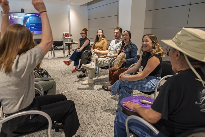 Two rows of people facing each other smile and cheer.