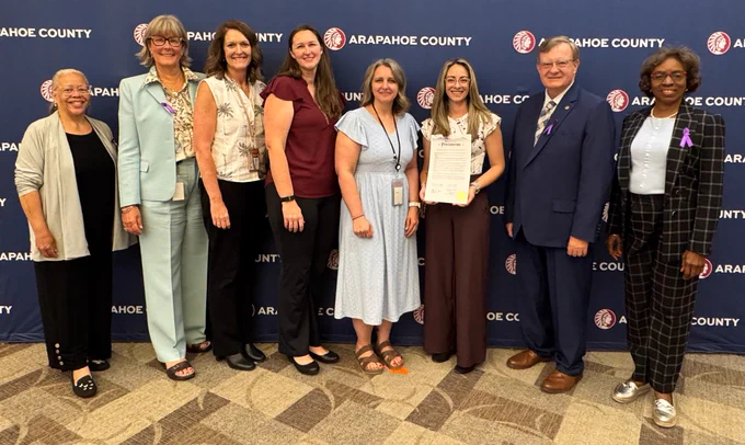 Group of people gathered with Arapahoe County Commissioners, with one person holding a proclamation honoring World Elder Abuse and Awareness Day