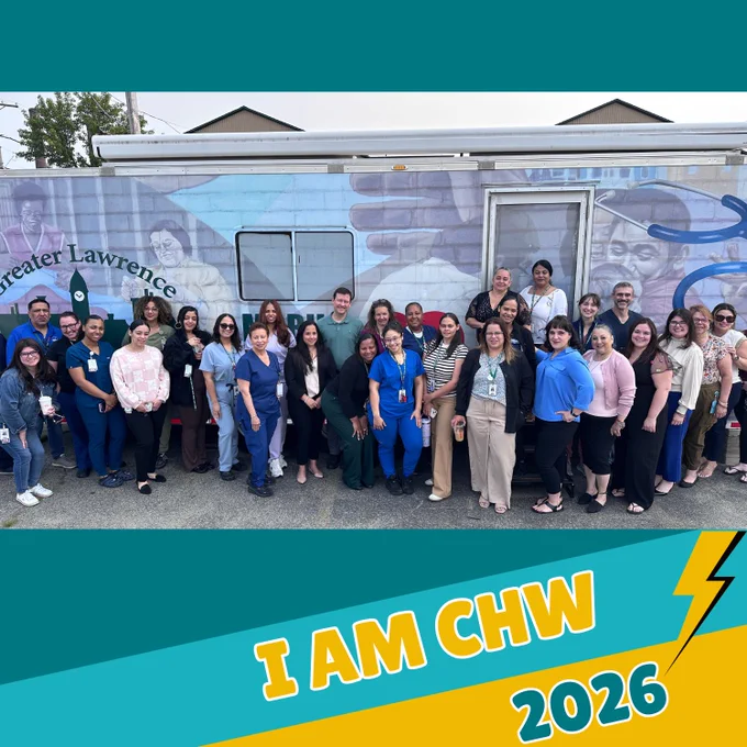 Group of diverse healthcare workers standing in front of a mobile clinic with a mural and 'Greater Lawrence Family Health Center' logo visible.