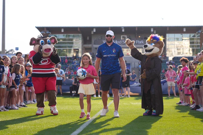 Jordan Staal and his daughter deliver the game ball at a match with Stormy and Roary mascots around them