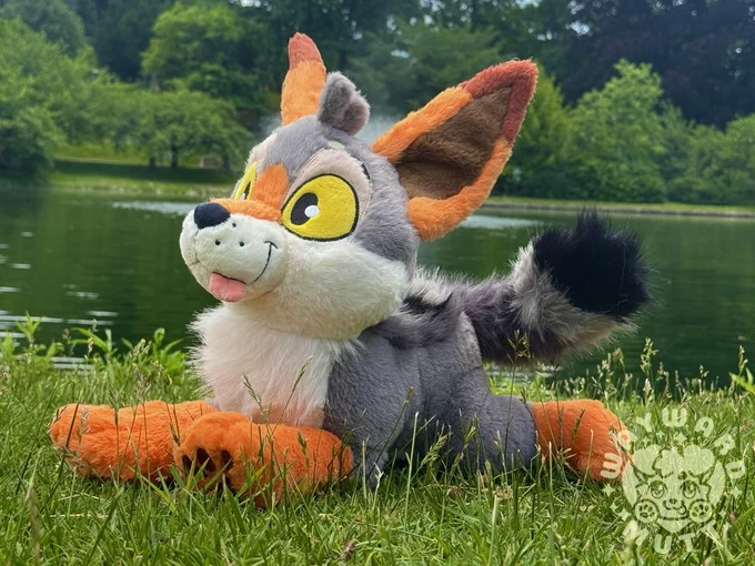 Yote plush laying in the grass looking up. there are no thoughts in that head. 