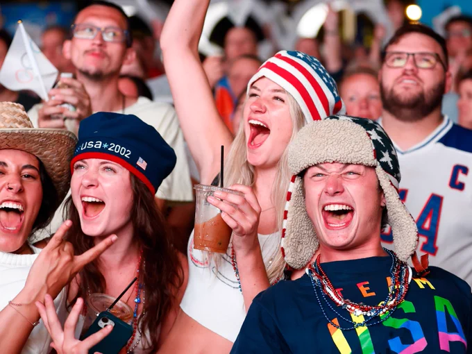 Team USA fans in the stands. One of the fans is wearing a t shirt that says Team USA in rainbow lettering