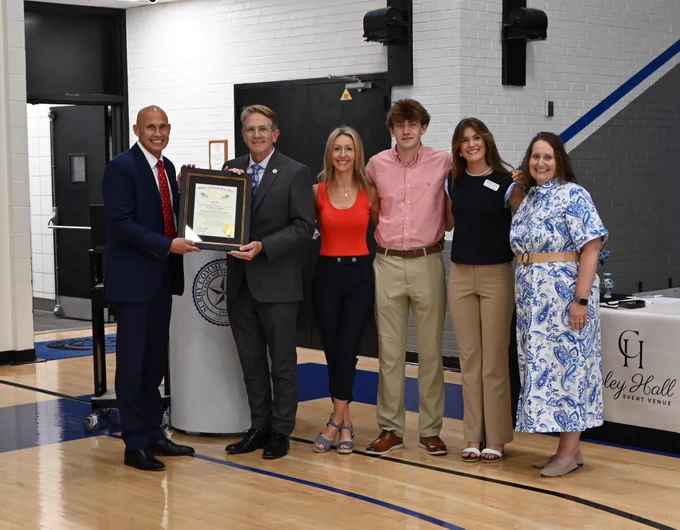 group photo with one man presenting a plaque to another man