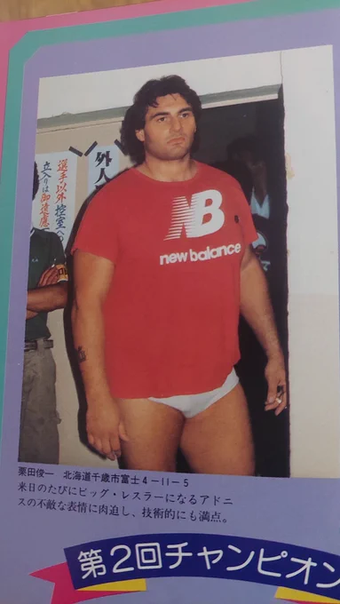adrian adonis with black hair, wearing white trunks, a bright red new balance t shirt and nothing else visible