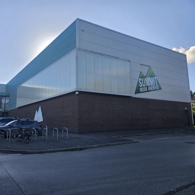 Summit Indoor Adventure building exterior with cars and bicycles parked outside.