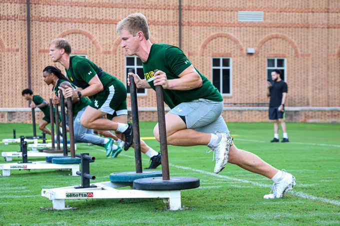 A group of William & Mary football players push weighted sleds at the Montgomery Football Practice Facility during summer workouts. 