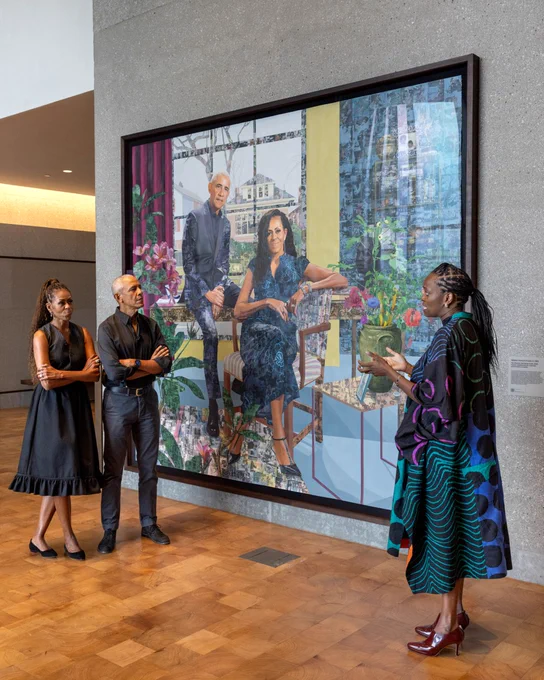 The Obamas look at their first-ever commissioned portrait together, painted by Njideka Akunyili Crosby, in the lobby of the new Obama Presidential Library. Njideka Akunyili Crosby is standing opposite the Obamas.