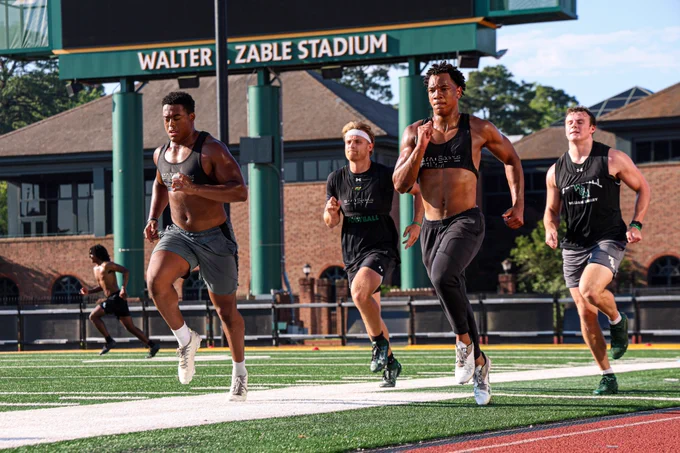 A group of four William & Mary football players run along the sidelines at Zable Stadium during summer workouts. 