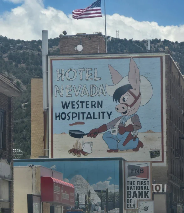 Mural on a building showing a cartoon donkey chef with a frying pan and campfire, advertising Hotel Nevada's western hospitality