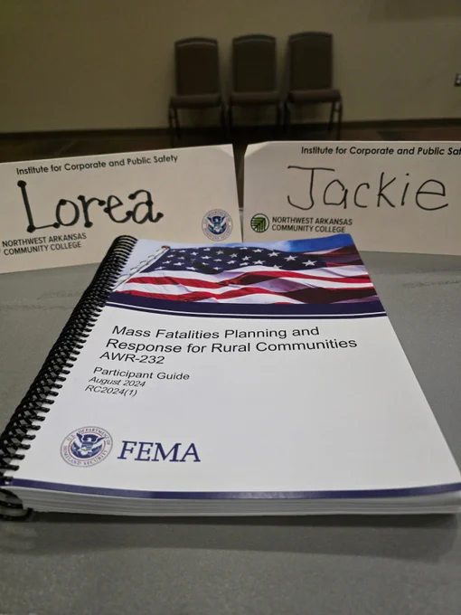 Spiral-bound FEMA guide with American flag cover, placed on table with two name tags reading Lorea and Jackie