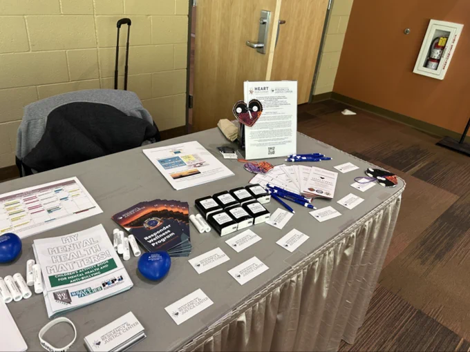 Table display with brochures, pens, and informational cards about mental health resources from the Resiliency & Justice Center