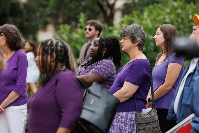 Photo of attendees at the press conference. Each person is wearing a different shade of purple, the symbolic color of Elder Abuse Awareness.
