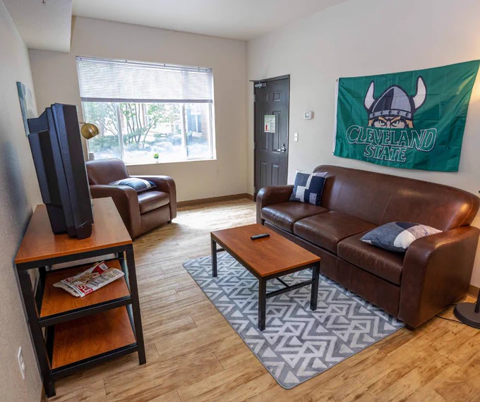CSU apartment living room with Cleveland State flag hanging above couch. 