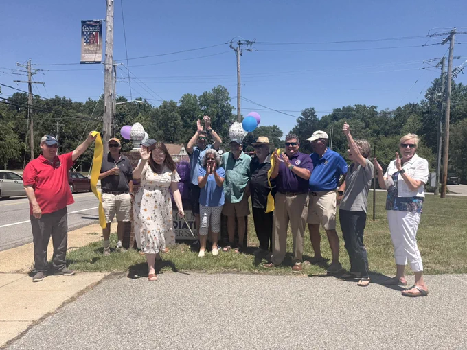 A group of people cutting a ribbon and celebrating.