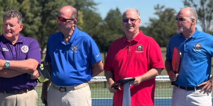 4 men standing on a pickleball court

