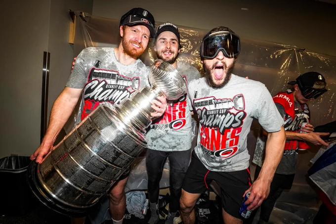 Frederik Andersen, Pyotr Kochetkov, and Brandon Bussi in the locker celebrating their Stanley Cup win. Andersen is holding the Cup.