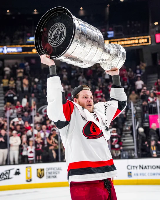 Eric Robinson on ice in a Hurricanes uniform lifting the Stanley Cup.