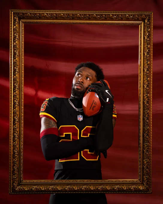 Photo of Trey Amos in a picture frame. He is holding a football up to his ear.