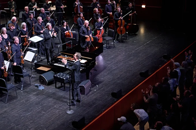 Ben Folds facing and applauding conductor Edwin Outwater and New Jersey Symphony musicians with the audience.