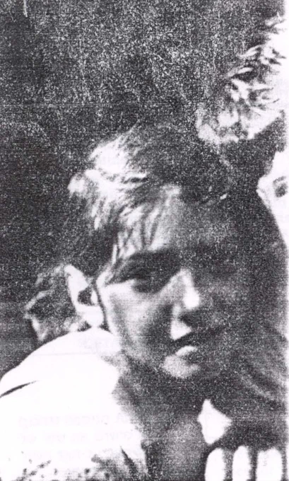 Black and white grainy image of a young girl with a focused expression.
