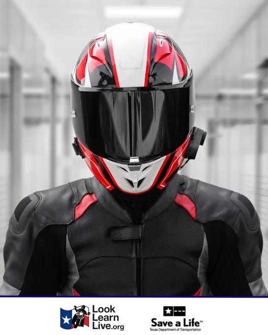 A person wearing a black and red motorcycle helmet and leather jacket stands in a hallway. The logos for "Look Learn Live" and "Save a Life: Texas Department of Transportation" are visible at the bottom.