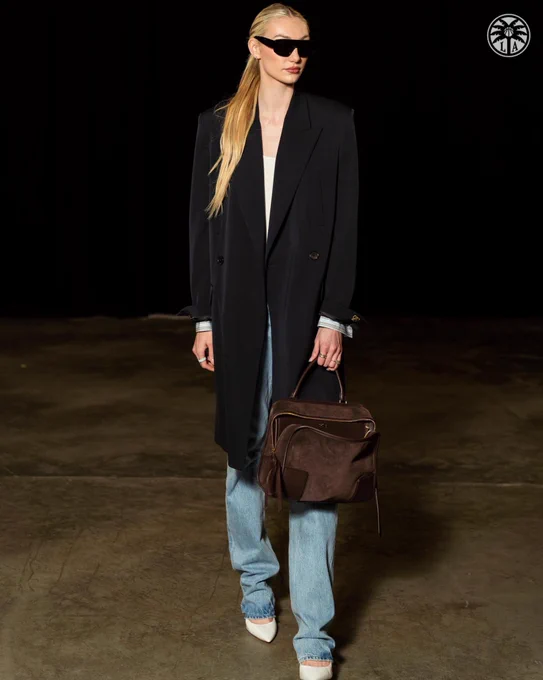 Cameron Brink wearing jeans and a pea coat and brown bag