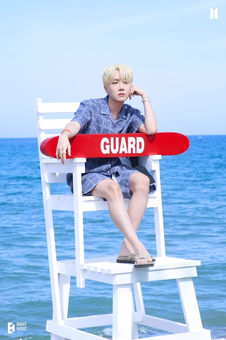 j-hope in a 2021 photoshoot for the butter single cd. he's sitting in a lifeguard chair facing away from the water looking like a model.