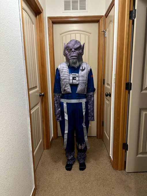 A photo of me standing in my parents hallway wearing the new Spirit Halloween Zeb costume and hyper-realistic latex mask.