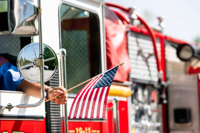 Firefighter waves an American flag out the window of a fire truck
