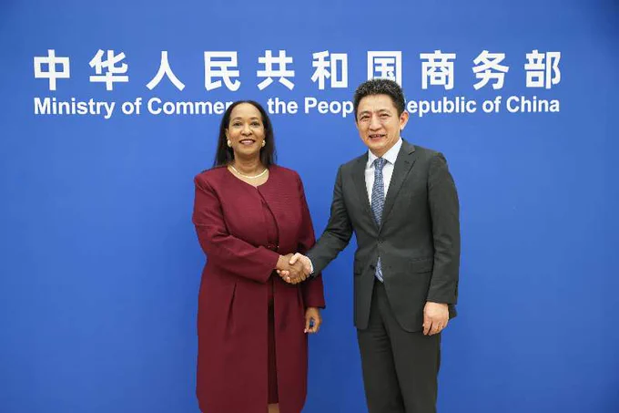 ITC Executive Director Pamela Coke-Hamilton (left) and China's Vice Minister of Commerce Chenggang Li (right) shake hands in front of the Ministry's media wall.