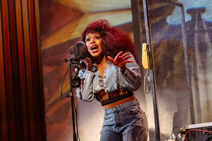 A photo showing a woman in denim get-up singing into a microphone 