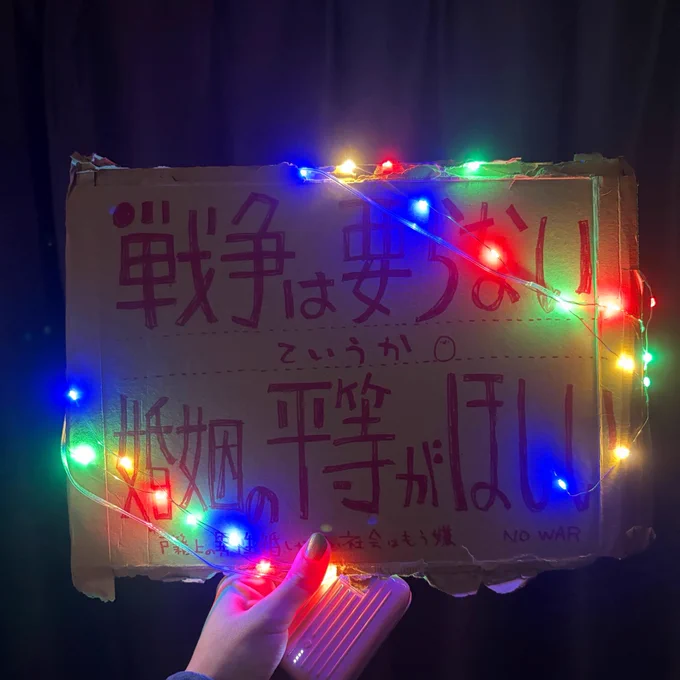 カラフルに光る電飾を段ボールのプラカードに雑に巻いて撮った写真