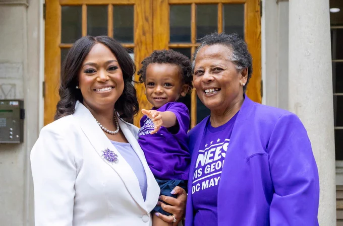 Two adults smiling and holding a small kid