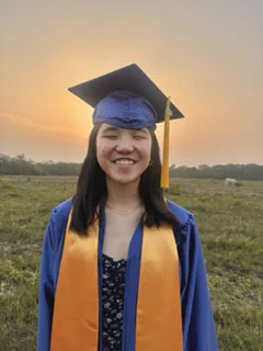 EmmaGrace wearing a blue cap and gown with a gold stole after graduating from High School in San Antonio.