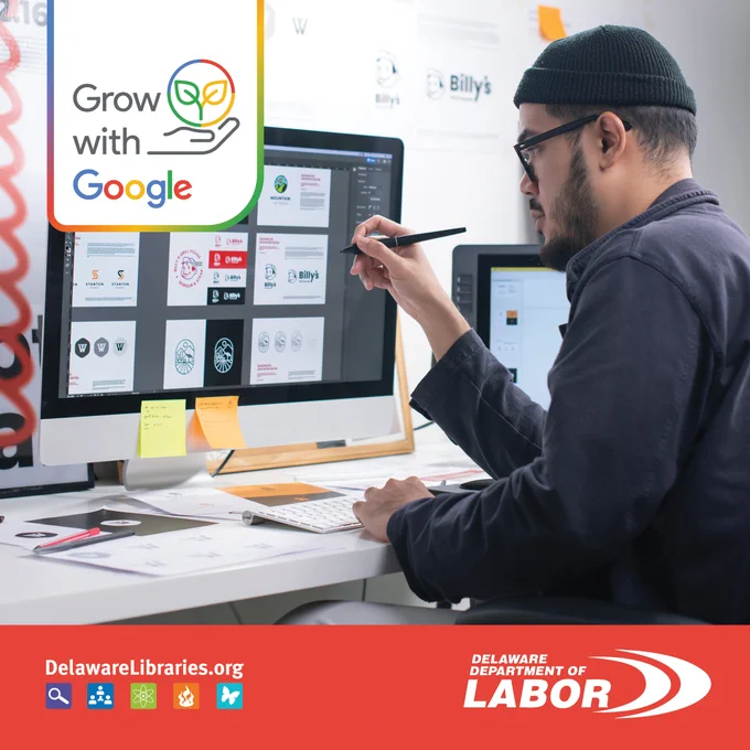 Designer working on logo concepts displayed on a large computer screen in a modern office setting.
